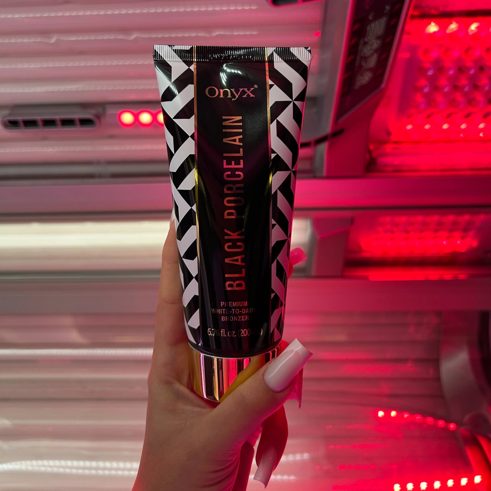 Woman in a swimsuit holding Onyx Black Porcelain White-to-Dark Bronzer inside a vertical tanning booth, preparing for an indoor tanning session.