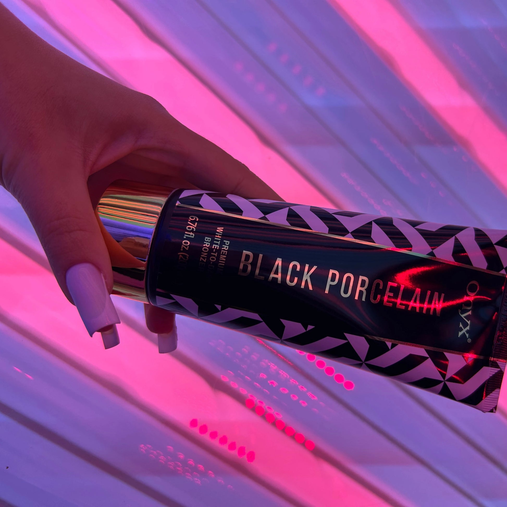 Onyx Black Porcelain White-to-Dark Bronzer held in front of a sunbed, highlighting its effectiveness in accelerating tanning results.