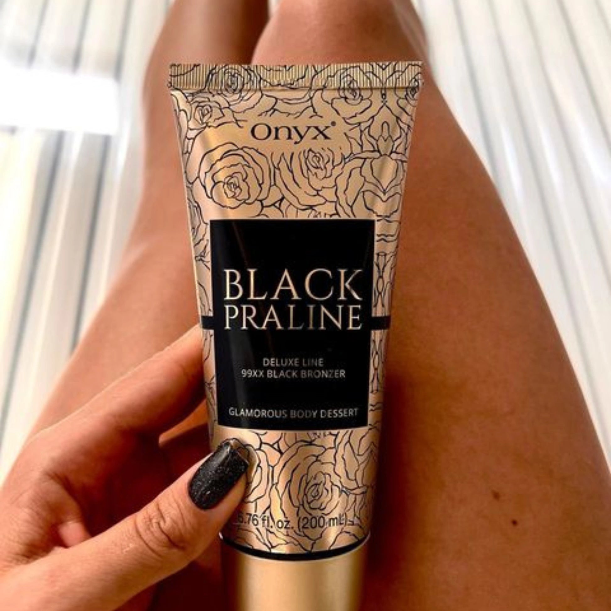 Model posing with Onyx Black Praline Bronzer Lotion in a tanning bed environment.