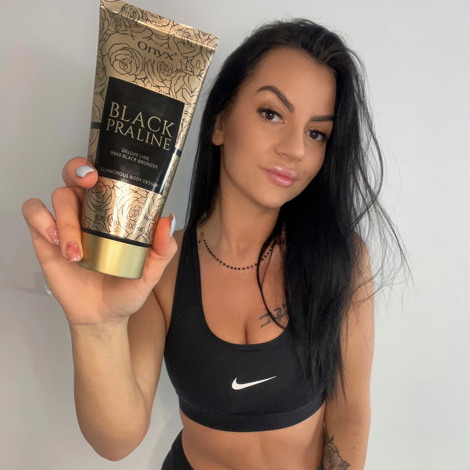 Fitness model promoting Onyx Black Praline Bronzer Lotion for a sun-kissed, deep tan.