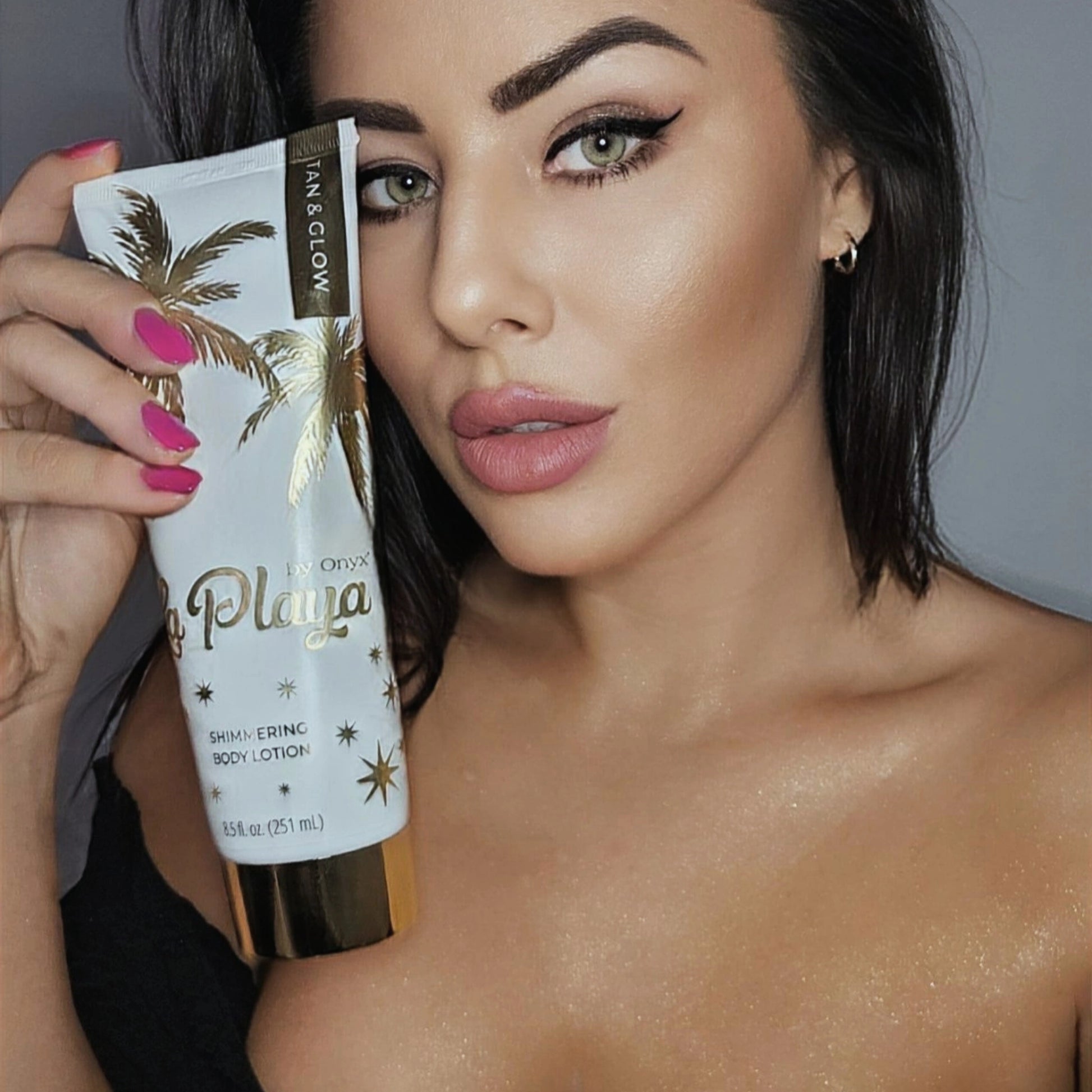 Close-up of a model holding Onyx La Playa lotion, highlighting radiant skin and golden shimmer.