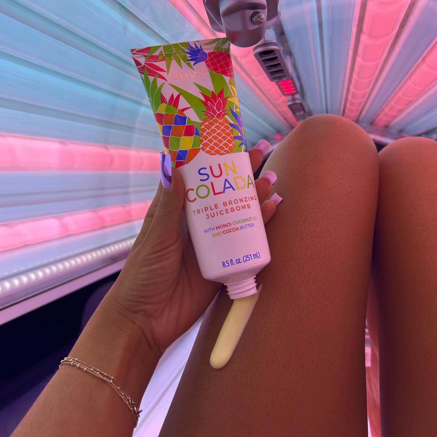 Onyx SunColada tanning lotion being applied to legs, enhancing melanin activation for a darker tan.