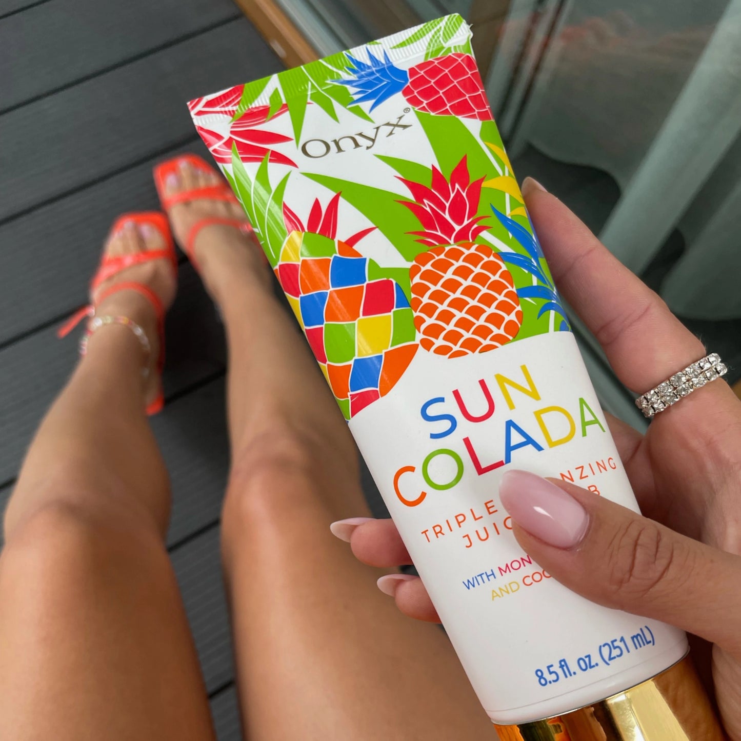 Onyx SunColada tanning bronzer being held close-up, emphasizing smooth, golden skin.