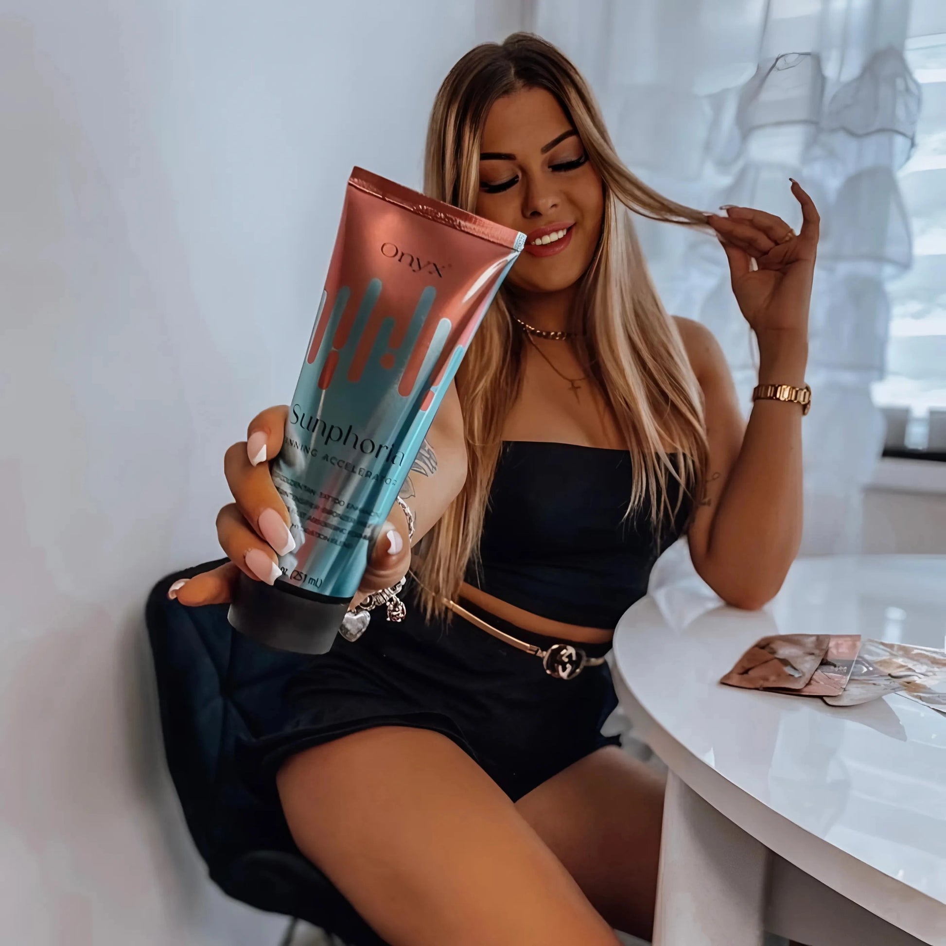Woman with flawless tan holding Onyx Sunphoria Tanning Accelerator.