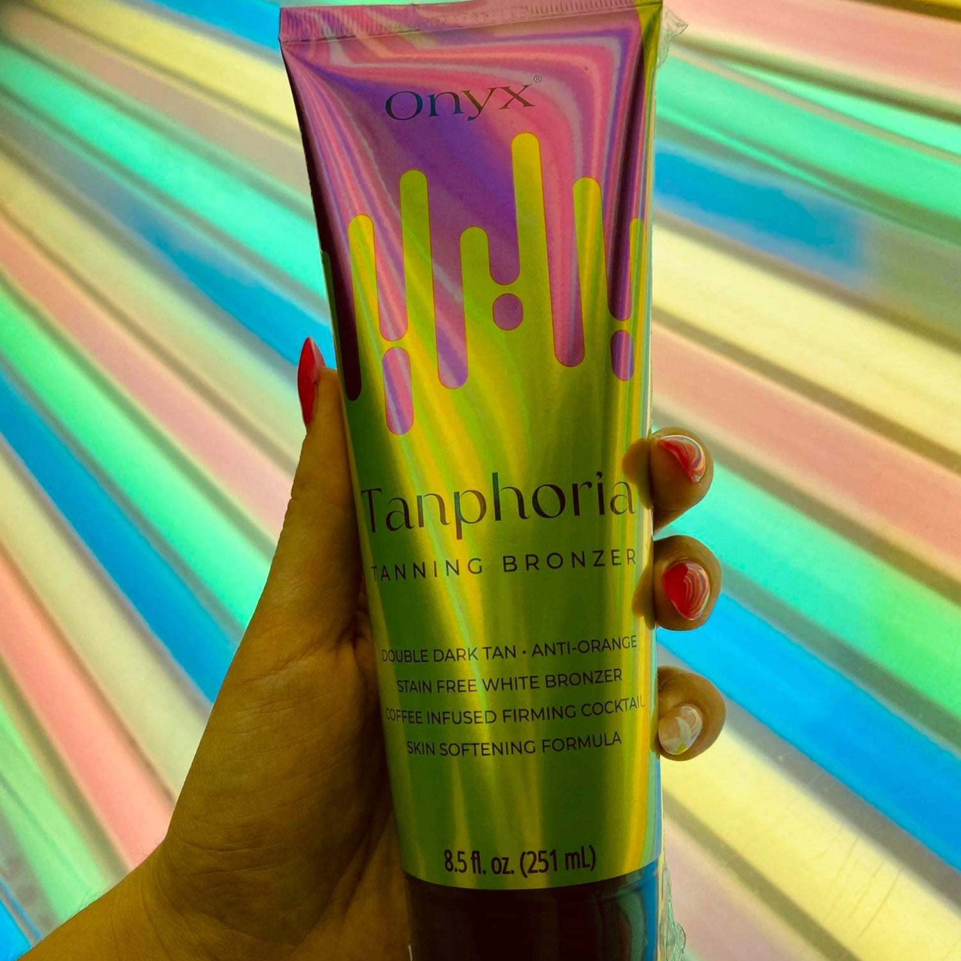 Onyx Tanphoria Bronzer Lotion held in front of a multi-color UV tanning booth.