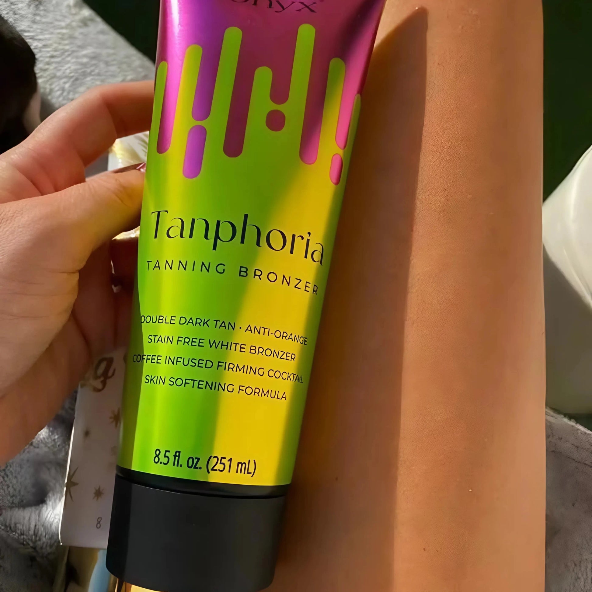 A close-up of Onyx Tanphoria Bronzer Lotion resting on tanned legs.