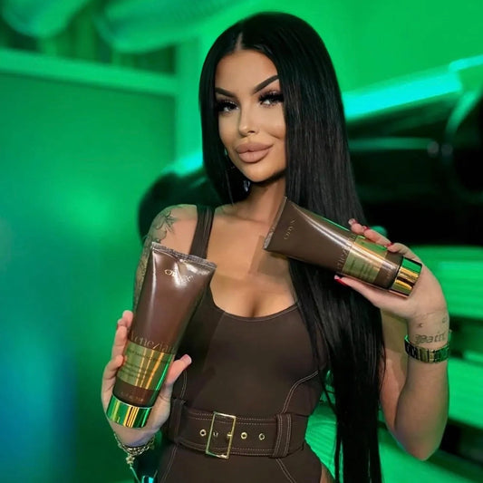 Woman holding two Onyx Veneziana intense tanning bronzer bottles with green accents against a green background