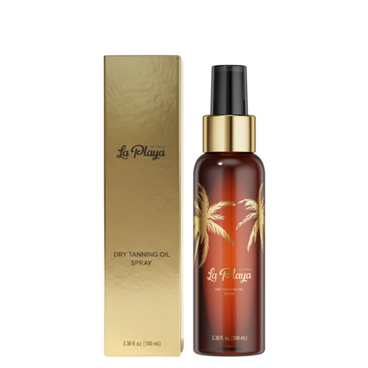 La Playa Dry Tanning Oil Spray bottle next to its metallic gold box, featuring gold palm tree illustrations on the amber bottle.