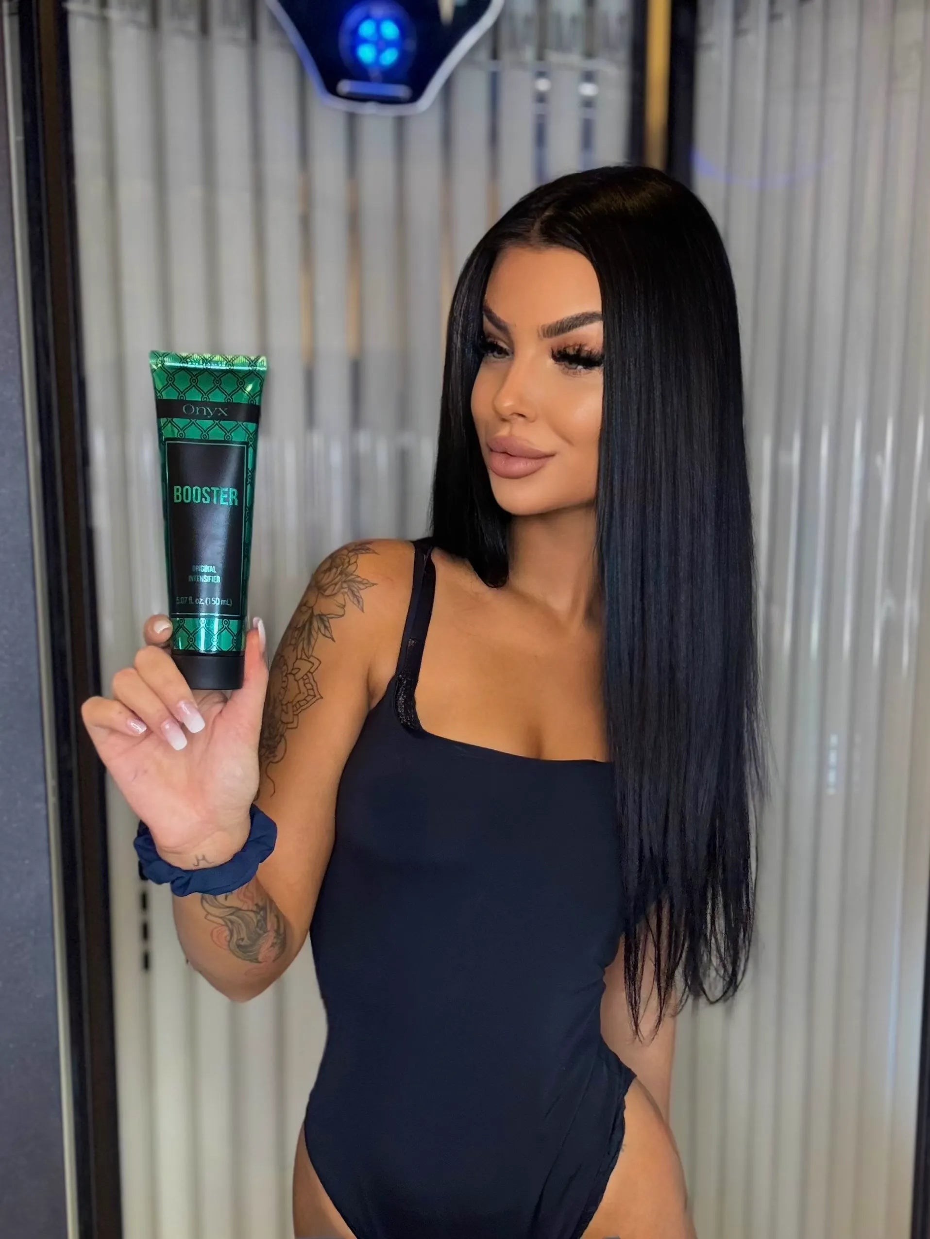 A woman holding Onyx Booster in a tanning salon. 
