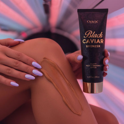 Applying Onyx Black Caviar bronzer lotion on leg in tanning bed