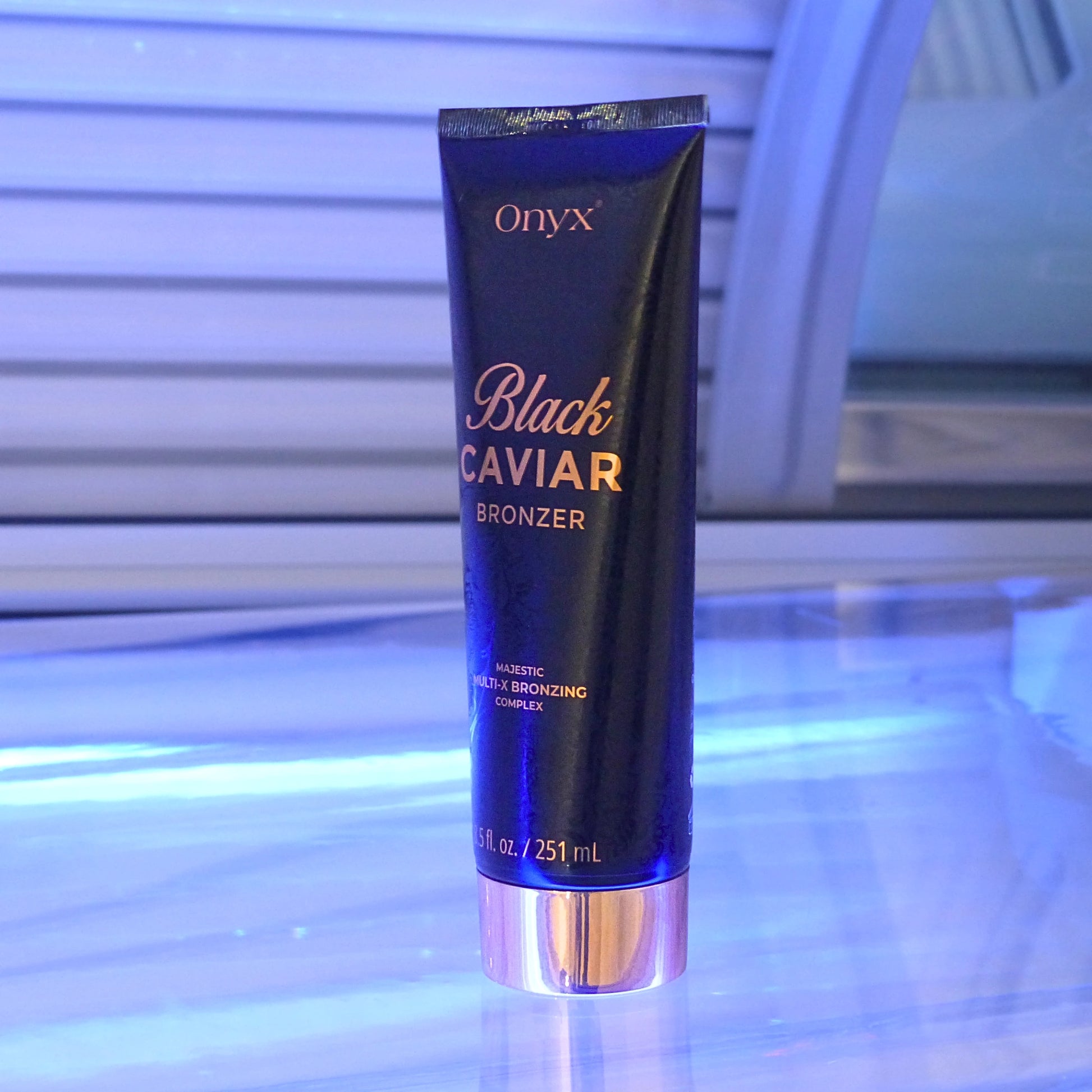 Onyx Black Caviar Bronzing Accelerator standing on a reflective surface inside a tanning booth, reinforcing its high-end tanning benefits.