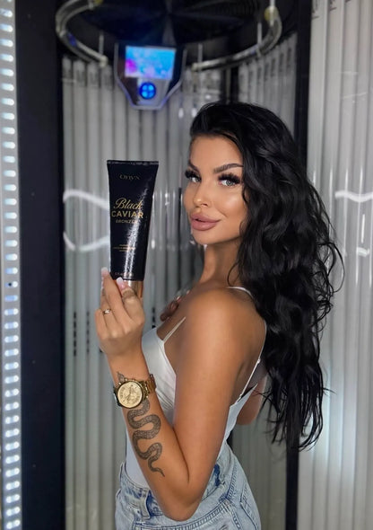Woman holding a Black Caviar product in front of a mirror with a hair dryer.