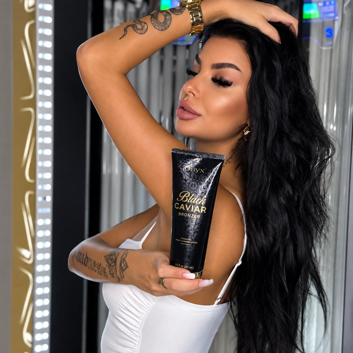Woman holding Onyx Black Caviar tanning bronzer inside an indoor tanning salon