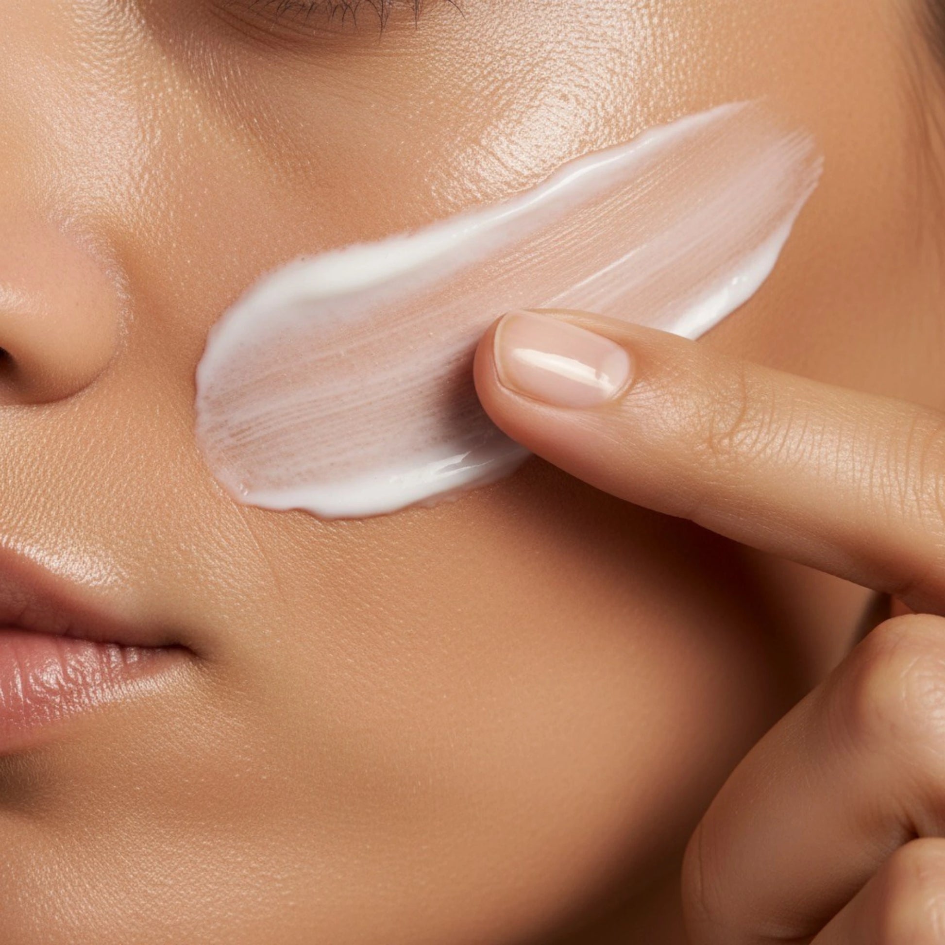Close-up of facial tanning cream being applied to skin with a fingertip