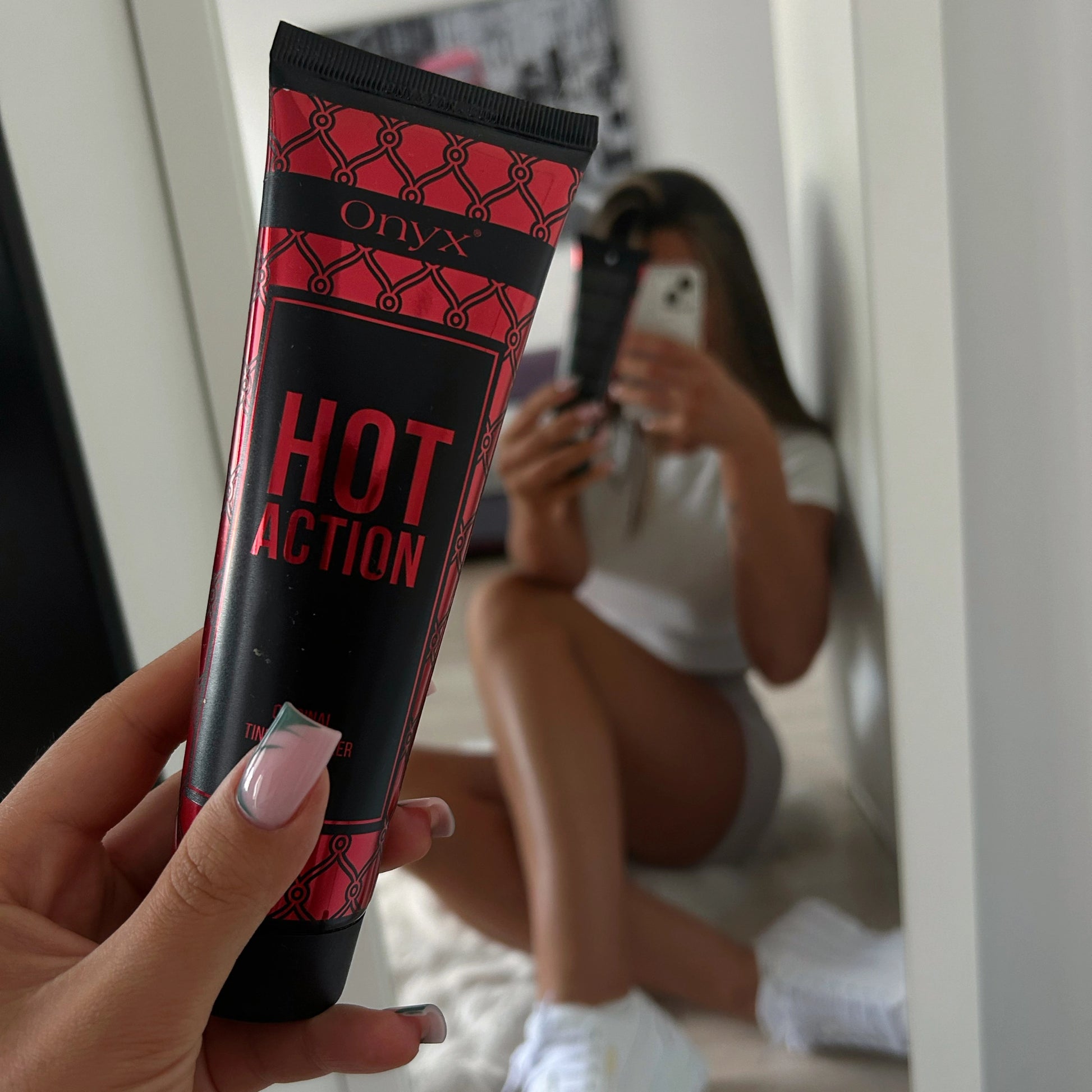 A customer taking a mirror selfie while showcasing the Onyx Hot Action Tingle Bronzer in a modern indoor setting.