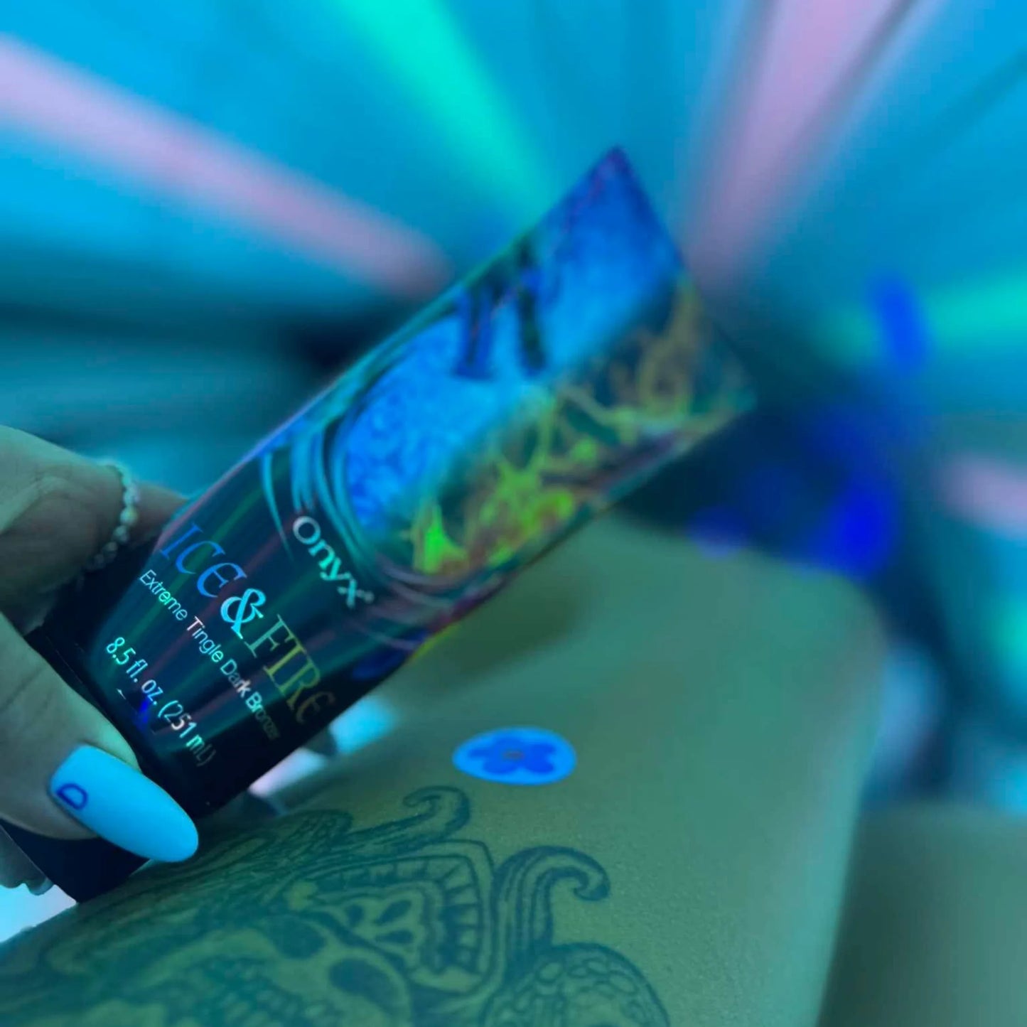Onyx Ice & Fire tanning lotion under UV lighting creating colorful glow during tanning session.