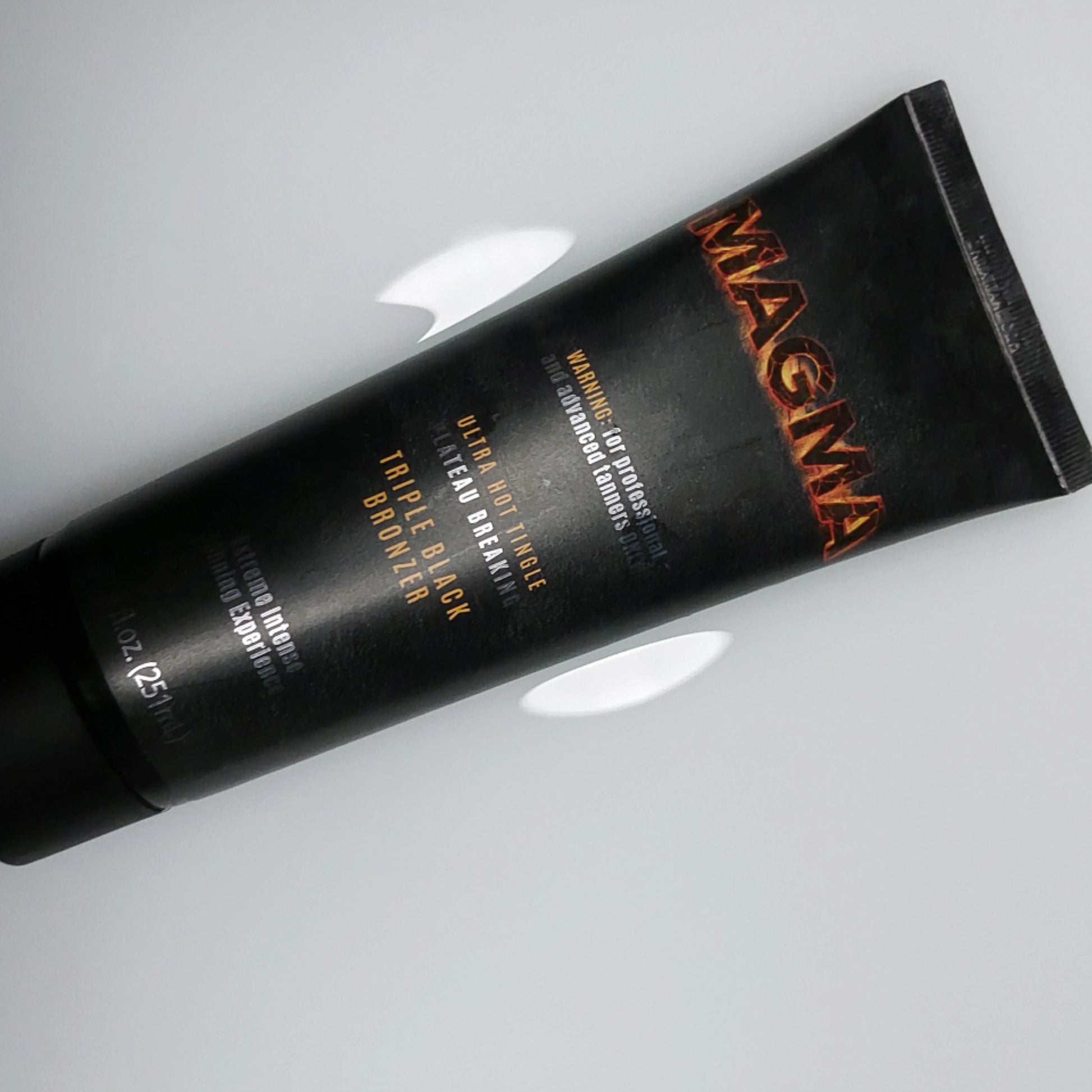 Onyx Magma triple black bronzer tube on a sleek surface, designed for professional tanning results.