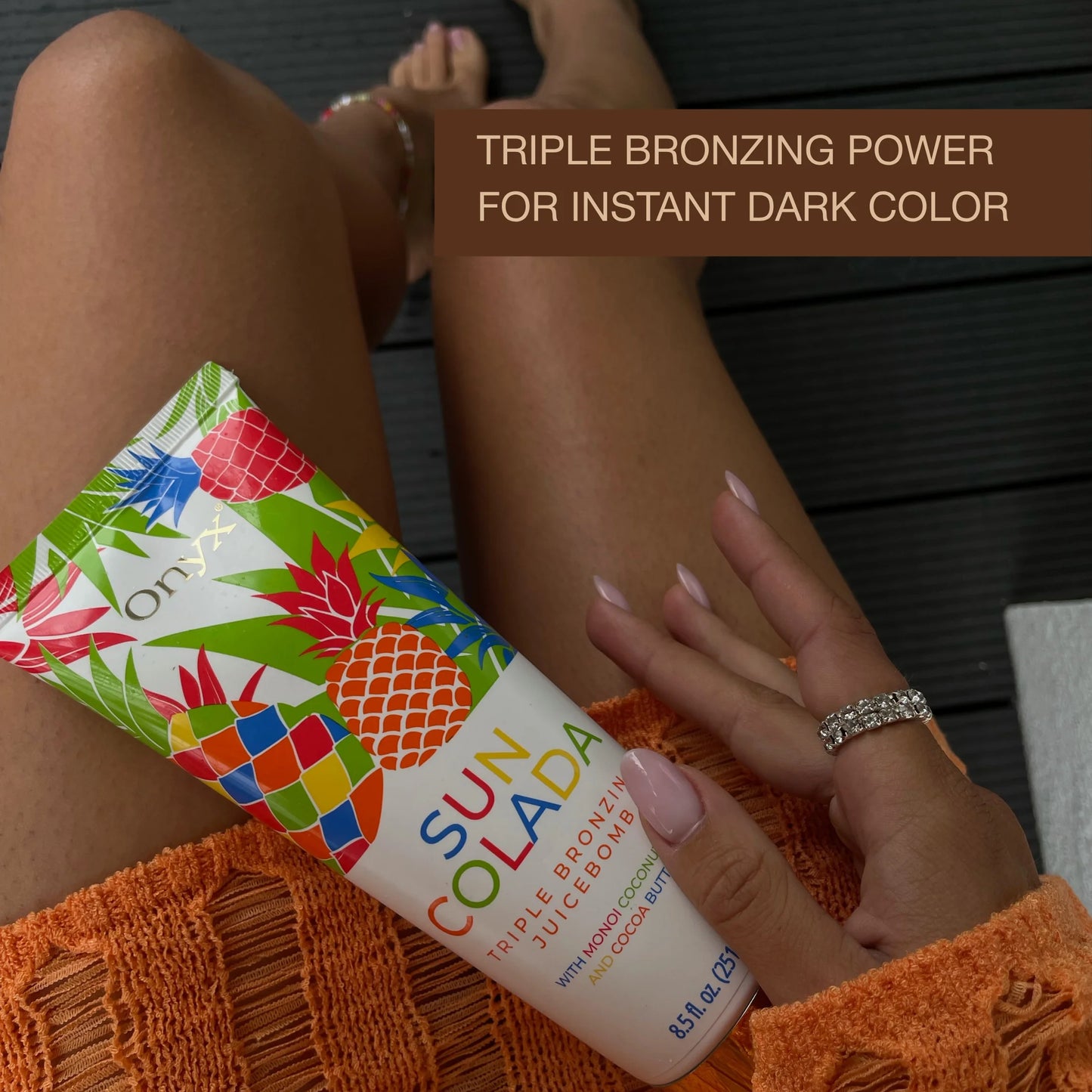Onyx Suncolada Triple Bronzing Juicebomb tanning lotion on tanned legs with triple bronzing power for instant dark color text