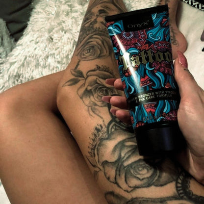 Onyx Tattoo Tanning Lotion held against tattooed legs, enhancing ink longevity and deep tanning effects.