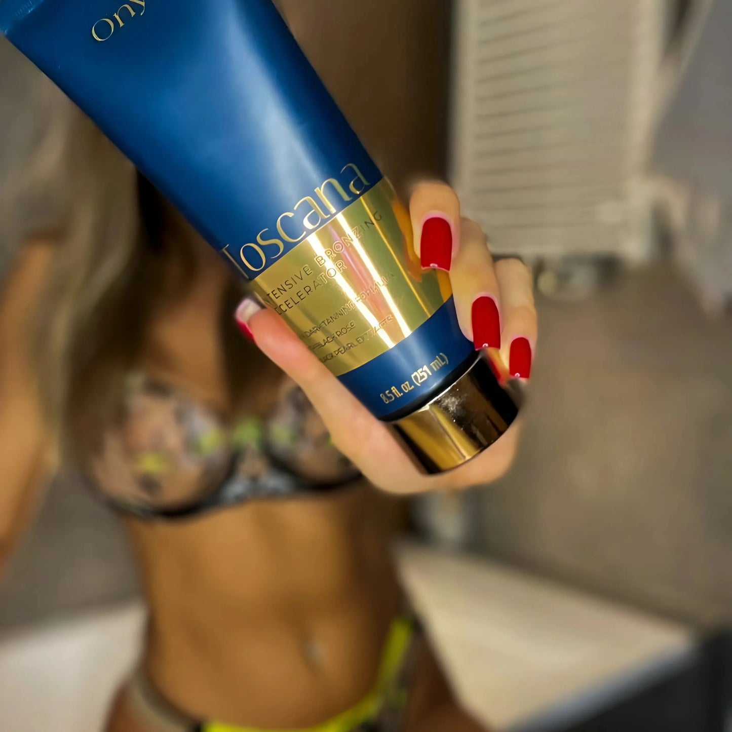 Onyx Toscana Bronzing Accelerator being held near bronzed skin, enhancing deep, sun-kissed color.