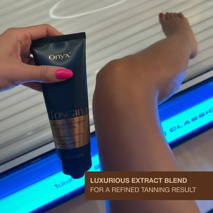 Hand holding Onyx Toscana Intensive Bronzing Accelerator near a tanning bed with luxurious extract blend message