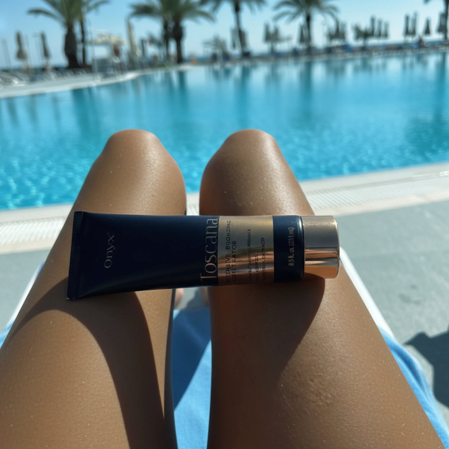 Onyx Toscana Intensive Bronzing Accelerator placed on tanned legs by a swimming pool