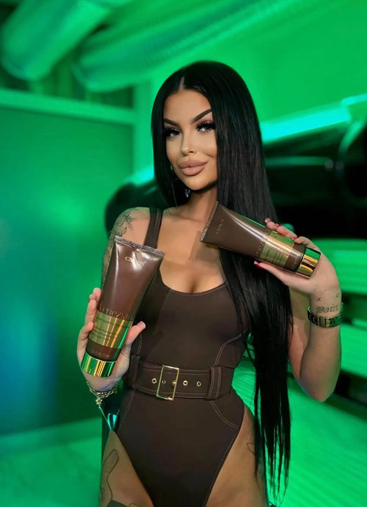 Woman holding two Onyx Veneziana intense tanning bronzer bottles with green accents against a green background