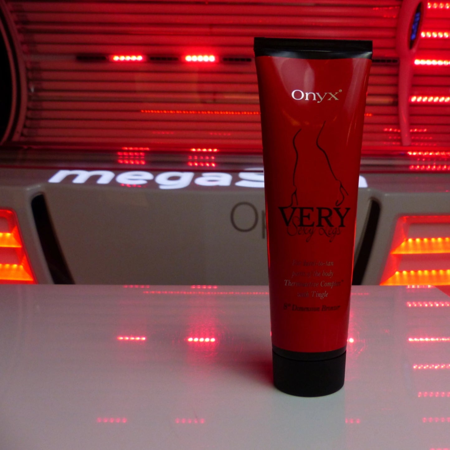 Onyx Very Sexy Legs Tingle Bronzer placed in front of a red-lit tanning booth for maximum effect.