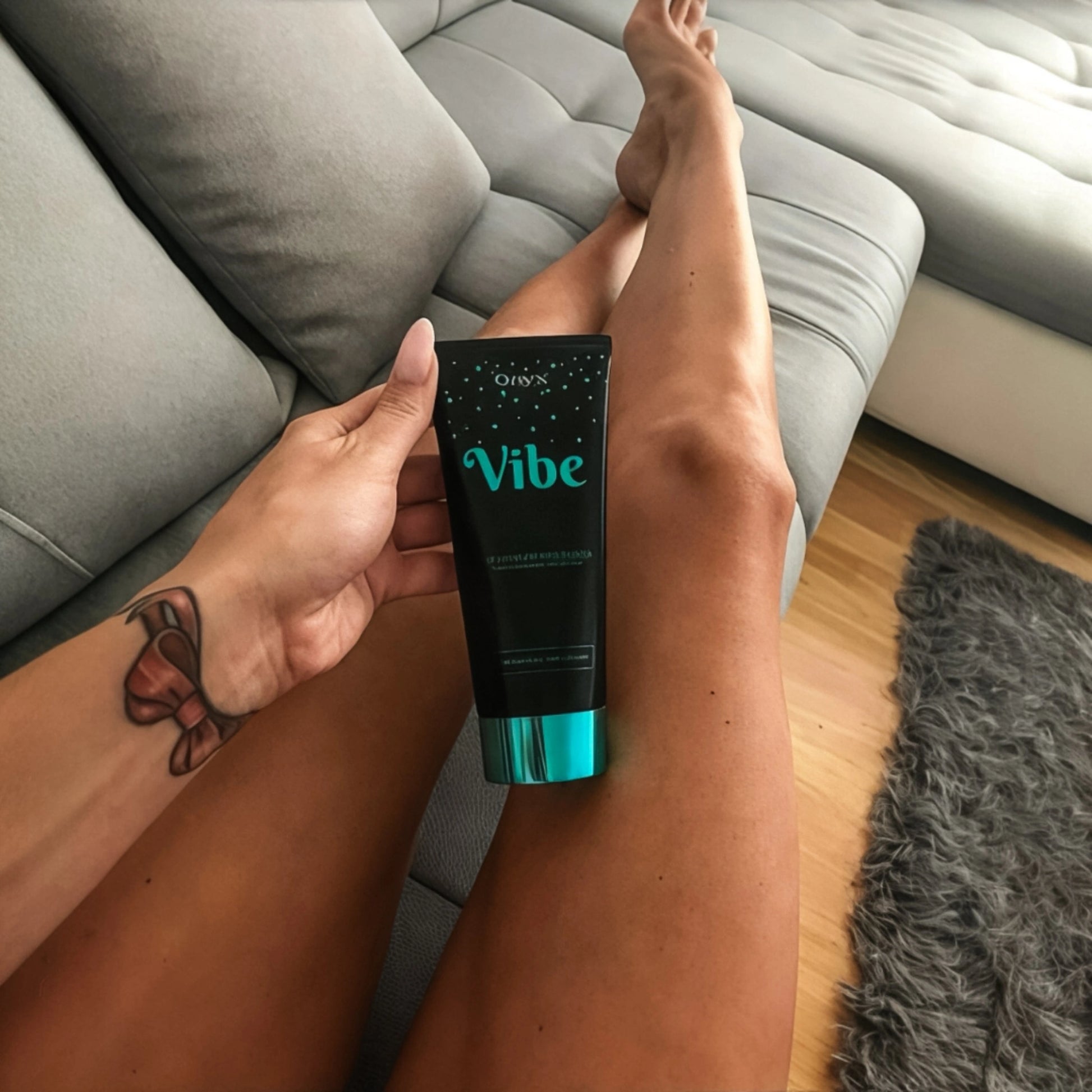 Onyx Vibe Tanning Accelerator resting on tanned legs, highlighting its ultra-dark tan effect.